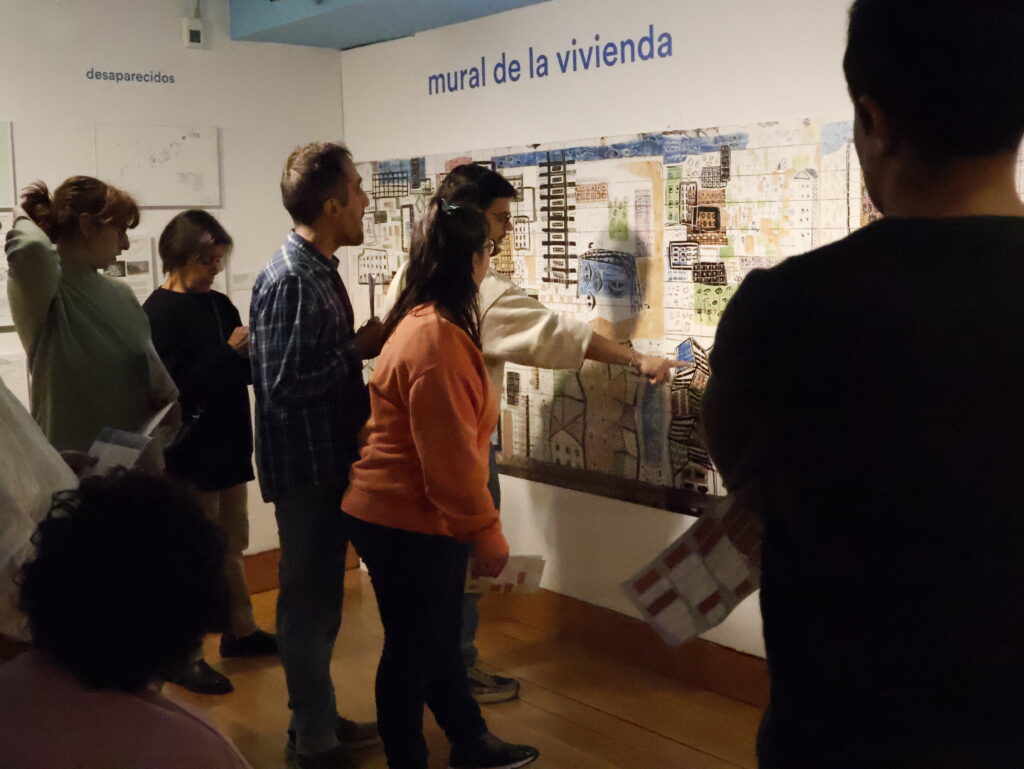 Visitantes ante el mural de la vivienda en una exposición