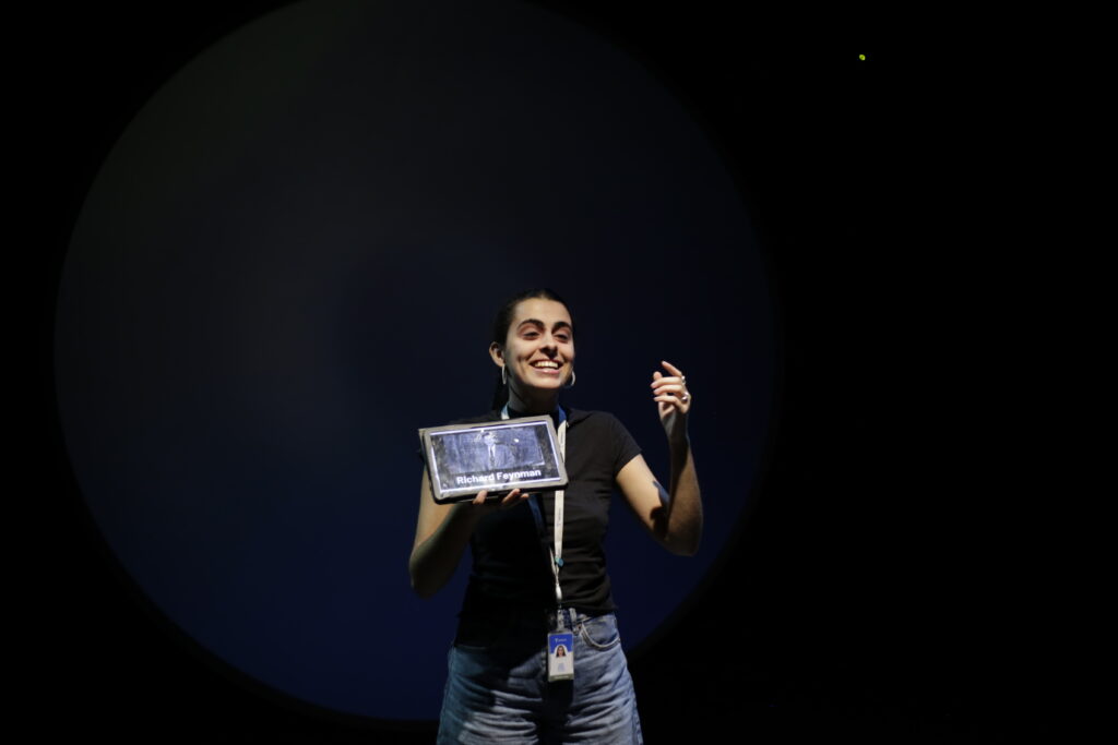 Una mediadora muestra una tableta iluminada en una sala a oscuras